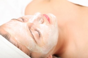 A picture of a young relaxed woman with a facial mask on over white background